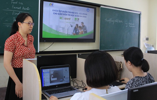 A person standing in front of a group of people using laptopsDescription automatically generated with low confidence