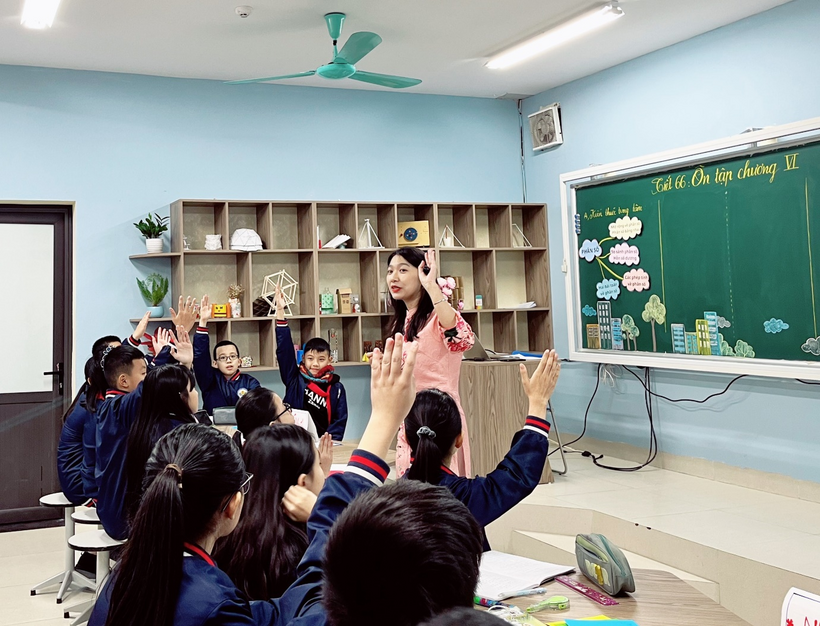 A person raising her hands in a classroomDescription automatically generated