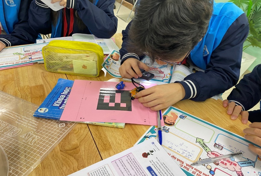 A child sitting at a table with a book and a penDescription automatically generated