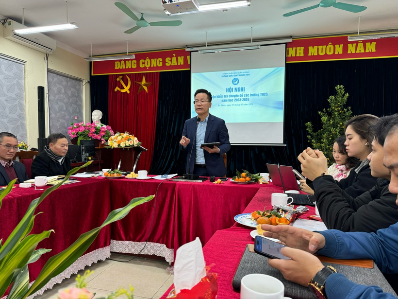 A person standing in front of a table with people sitting around itDescription automatically generated