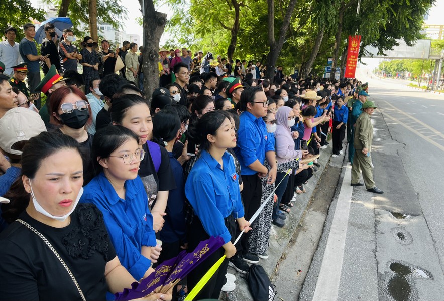 A group of people standing on the side of a road

Description automatically generated