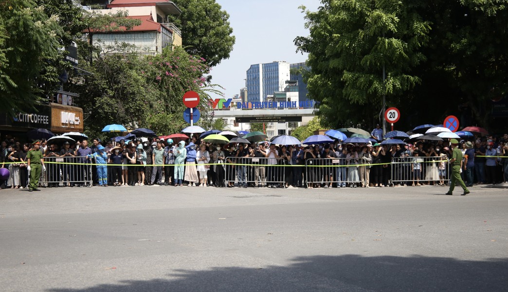 A group of people standing in a line with umbrellas

Description automatically generated