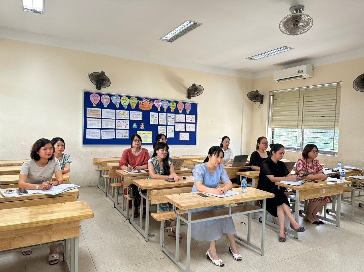 A group of people sitting at desks in a classroom

Description automatically generated