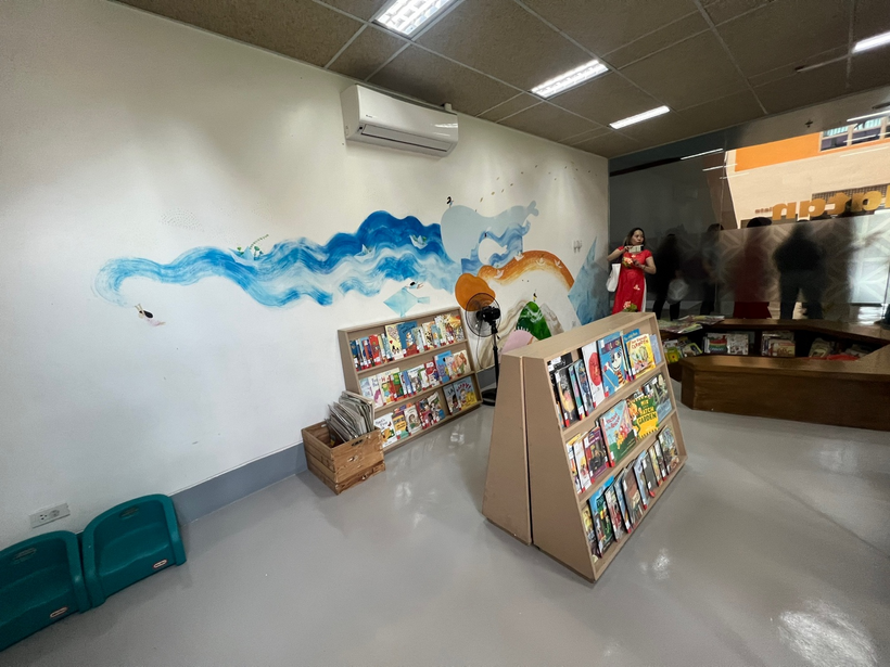 A room with a book shelf and a person standing in front of a wallDescription automatically generated