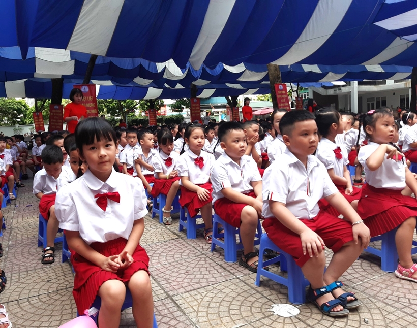 A group of children sitting on chairs under a blue and white tent

Description automatically generated
