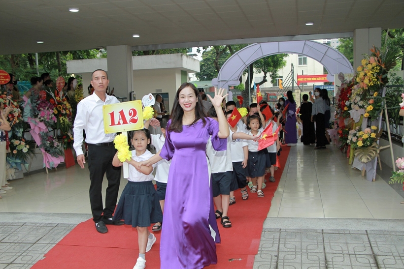 A person and children walking down a red carpet

Description automatically generated