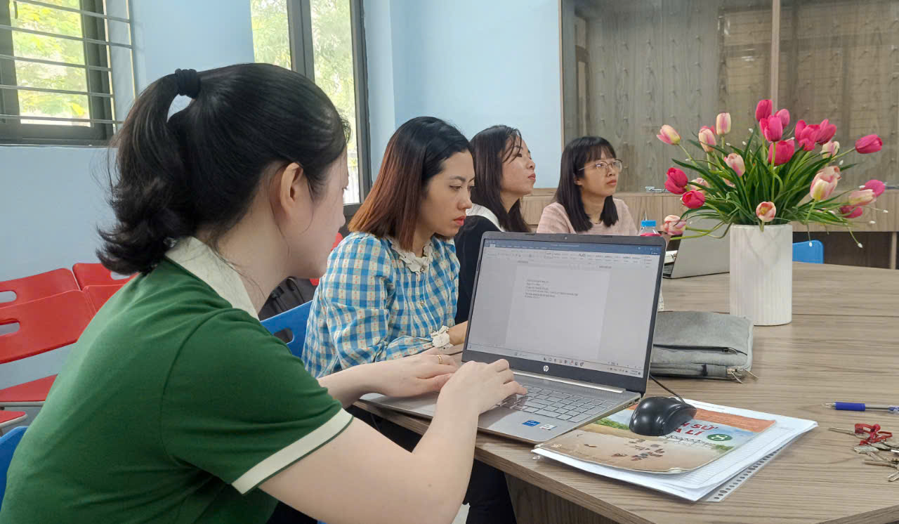 A group of women sitting at a table using a computerDescription automatically generated