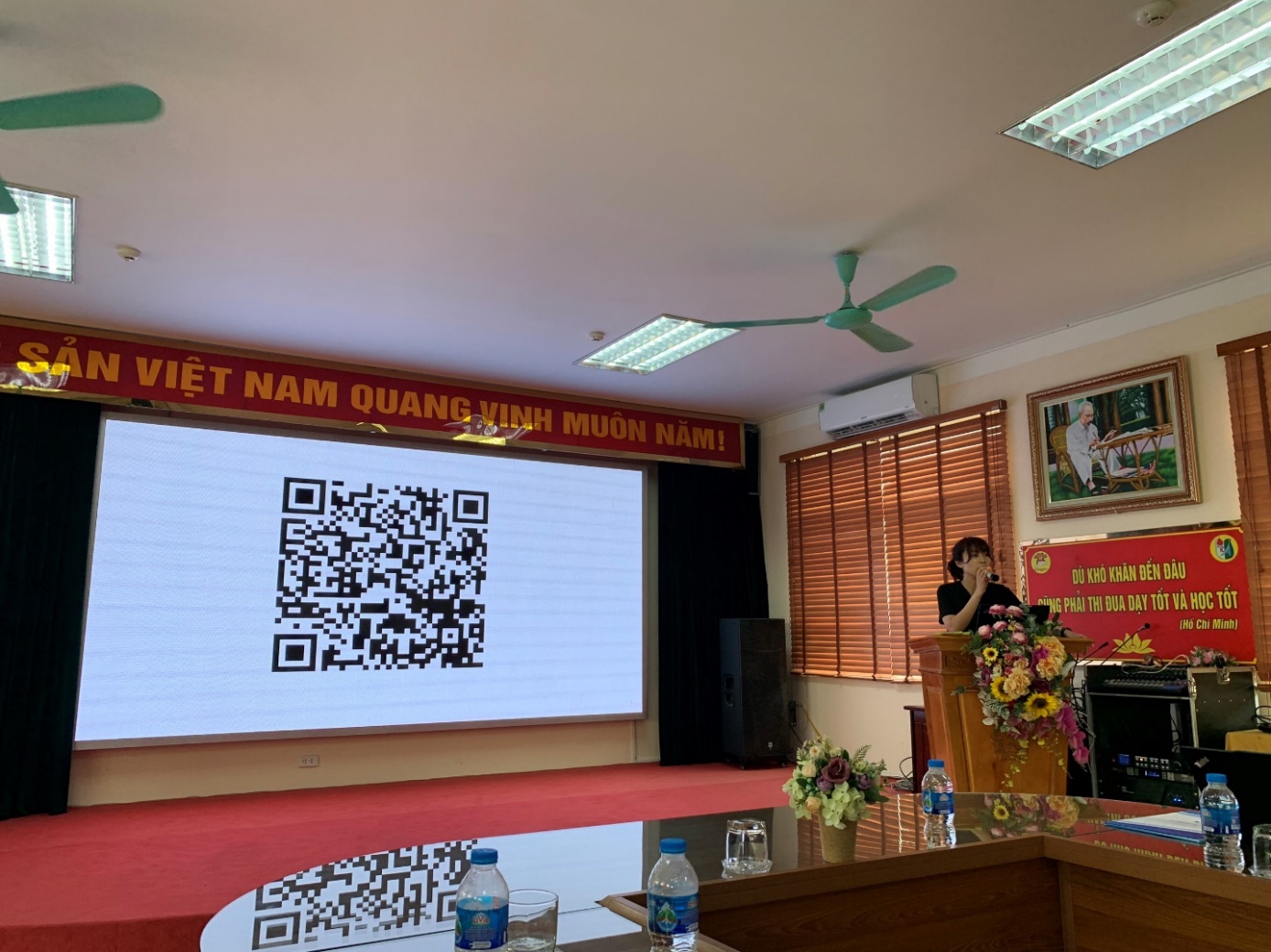 A room with a screen and a person standing in front of it

Description automatically generated