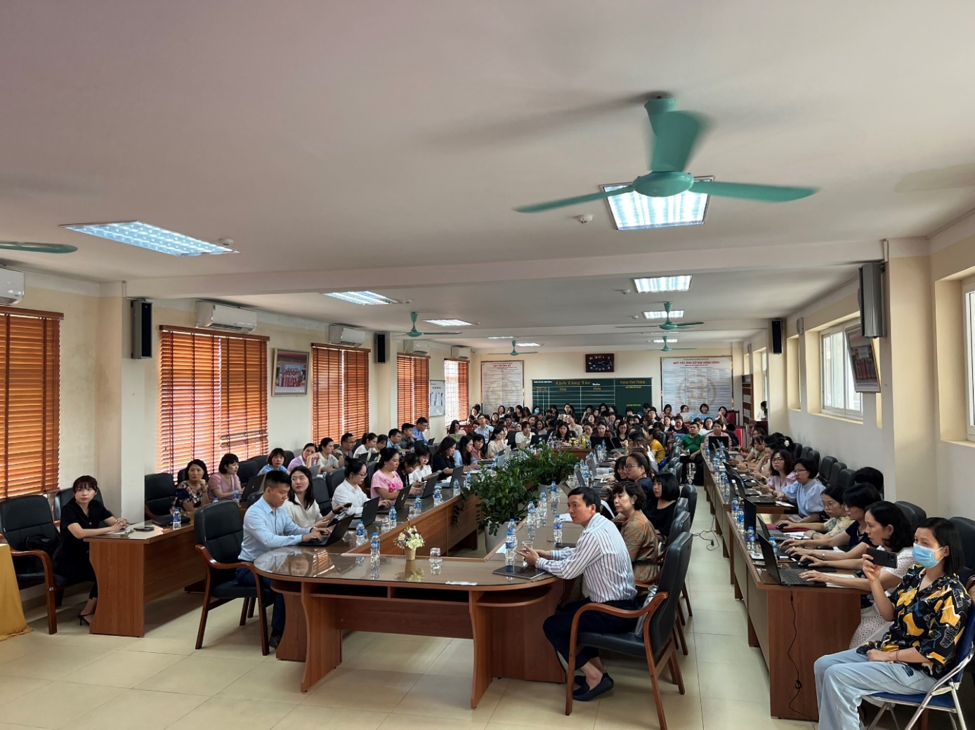 A large group of people sitting at long tables

Description automatically generated
